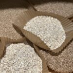 This photo is assorted grains in brown paper liners sitting on a butcher block counter top.