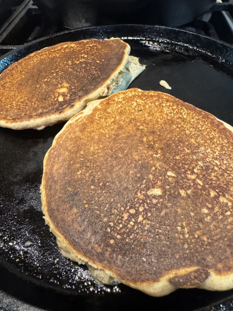 Pancakes made with fresh milled flour cooking on a cast iron skillet
