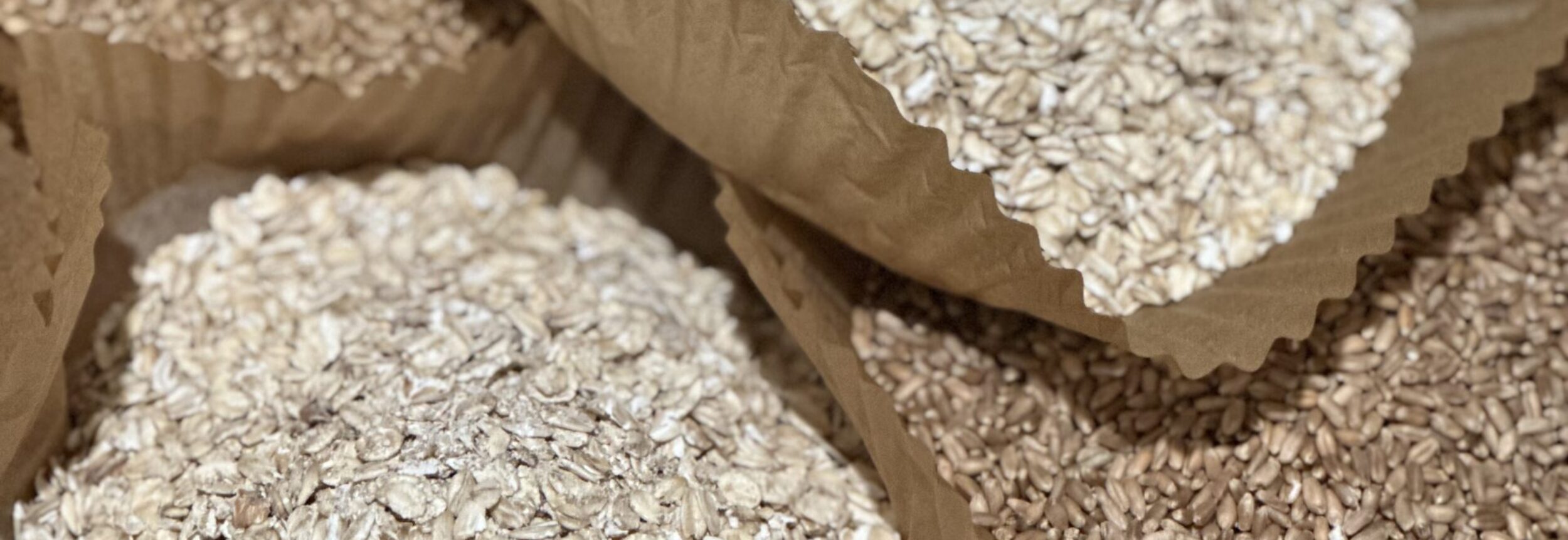 this image is large parchment brown cupcake liners filled with assorted grains of different colors. they are sitting on a butcher block counter top