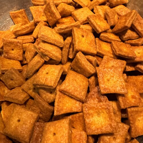 This image is of a silver bowl full of orange colored, cheese crackers made with fresh milled flour.