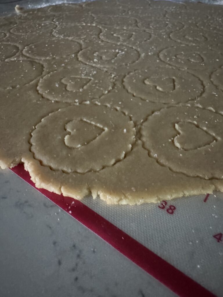 This image is of a silicone mat with a red line and numbers. There is cookie dough rolled out and with cut out cookies.