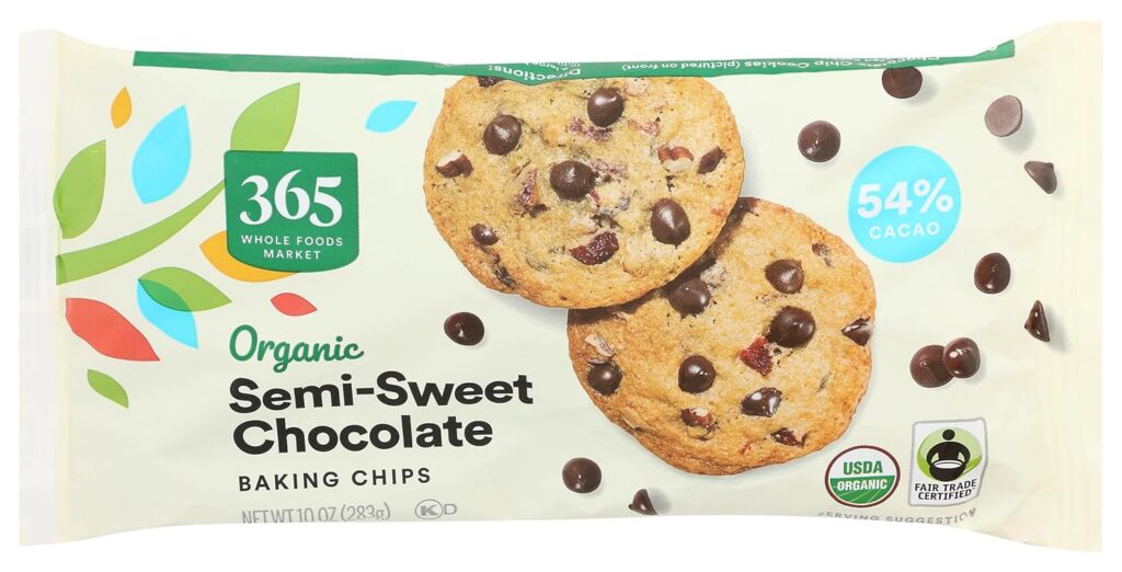 This image is of a cream colored rectangular bag of chocolate chips. The brand is 365 organics, semi sweet chocolate. There is an image of 2 chocolate chip cookies on it and a few chocolate chips.