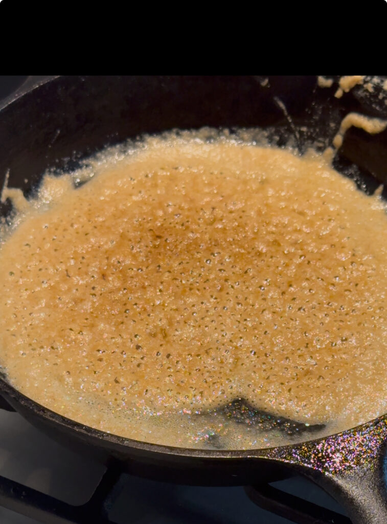 This image is of a flour and butter roux cooking in a cast iron skillet. It is very bubbly