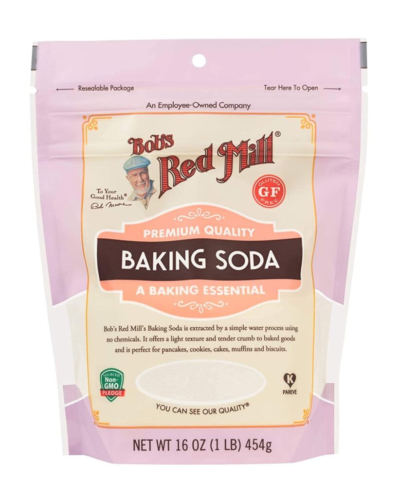 This image is of Bob's Red Mill Baking Soda. It is a pink bag, with wred writing, a blue section in the middle and a brown ribbon across the blue section stating the item is BAKING SODA.