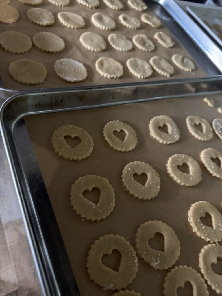 This image is of 2 pans lined with parchment paper and round cookies on top.