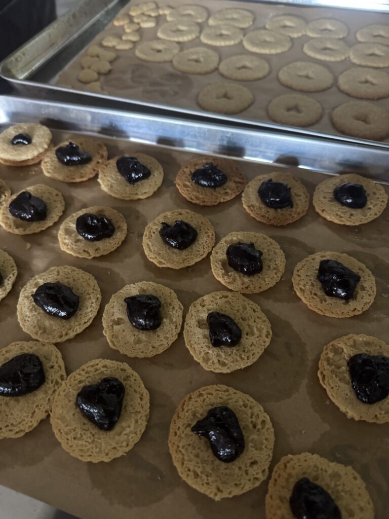 This image is of golden brown cookies with dark jam on top of them. 