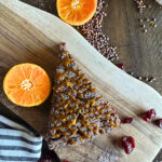 a piece of cake with oranges and spices on a wooden board