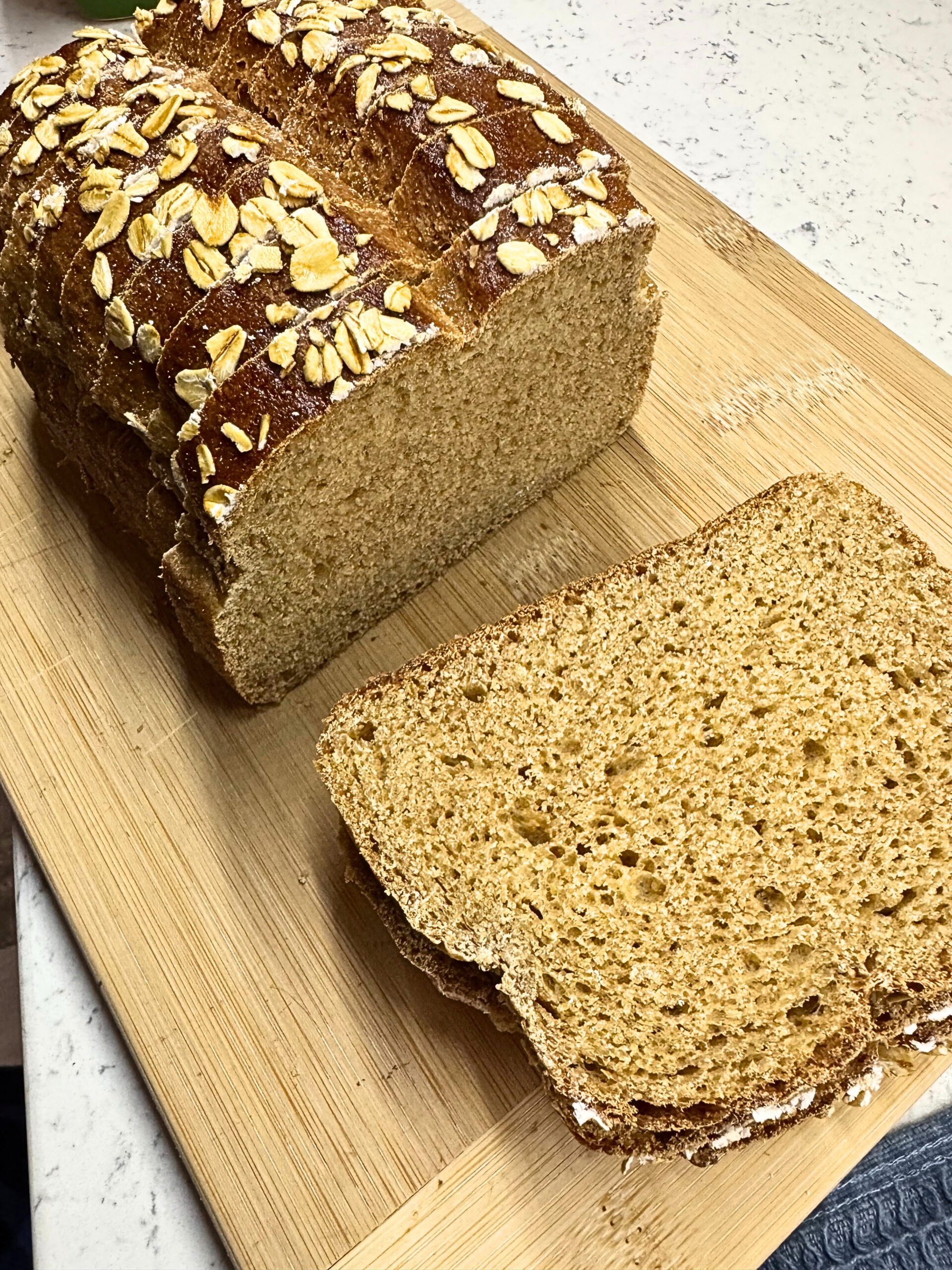 Honey Oat Wheat Bread loaf sliced on a wooden cutting board